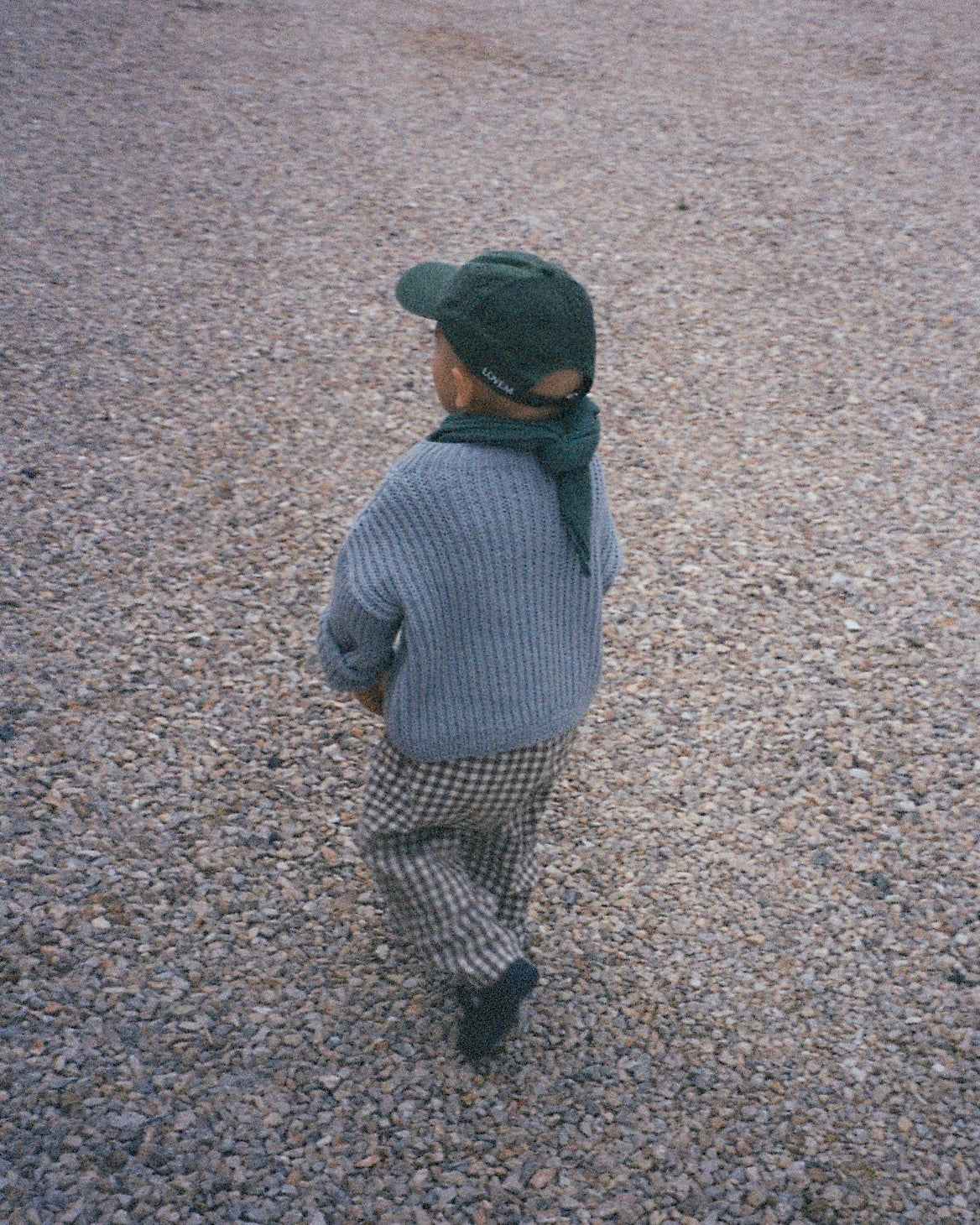 Kleiner Junge mit grünem Cap von LOVEM und hellblauem Pullover. 